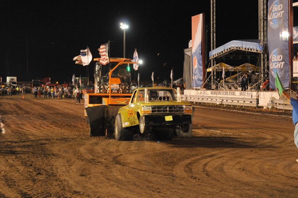 A yellow truck pulling a sled at the State Fair Grandstand