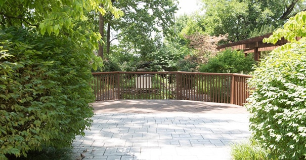 The sidewalk, greenery and railing at the Highway Gardens on a sunny day