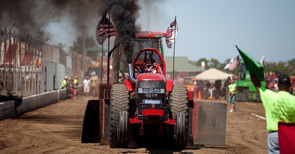 A man driving a red tractor in a tractor pull