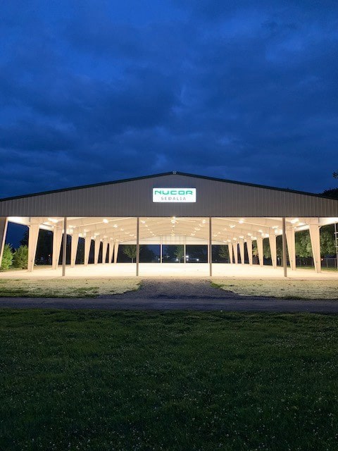 An exterior view of the Nucor Director's Pavilion lit up at night