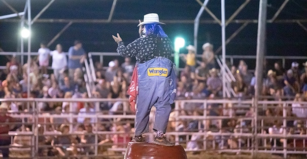 A rodeo clown standing on a barrel