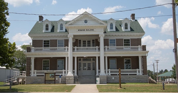 An exterior viewof the Womans Building, a large two story red brick building with white columns